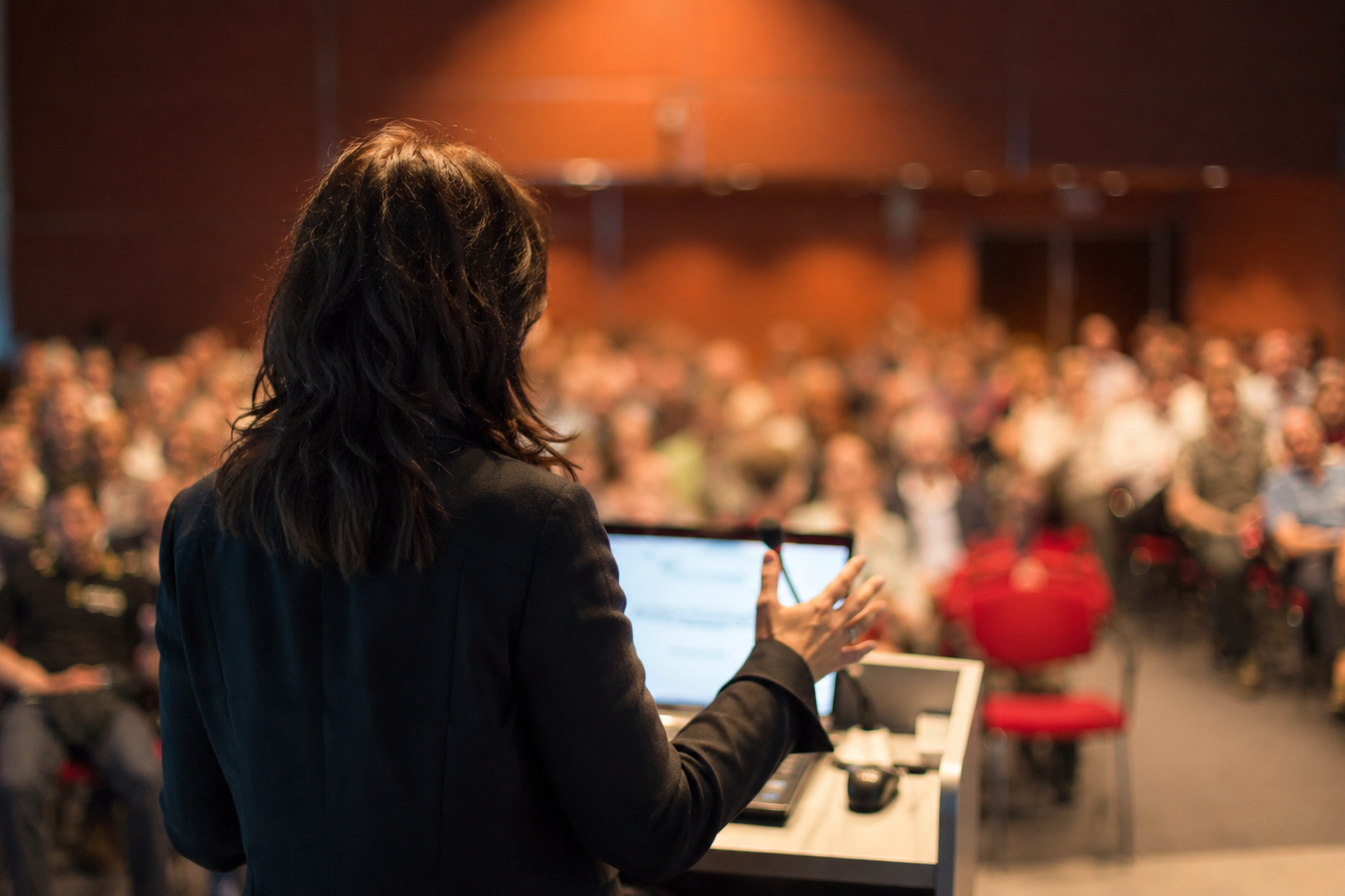 Speaker at a podium addressing a full conference audience